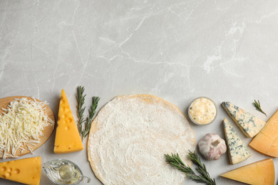 Photo of Flat lay composition with dough and fresh ingredients on grey marble table, space for text. Pizza recipe