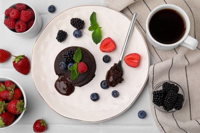 Plate with delicious chocolate fondant, berries and mint on white tiled table, flat lay