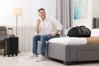 Photo of Smiling guest relaxing on bed in stylish hotel room