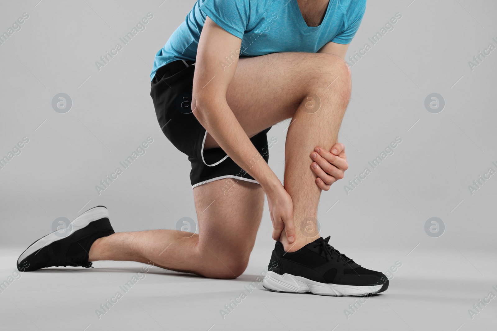 Photo of Man suffering from leg pain on grey background, closeup