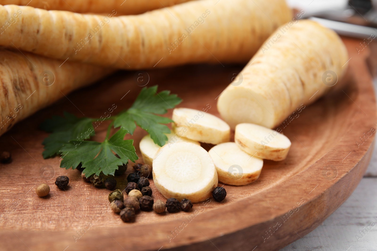 Photo of Raw parsley roots and fresh herb on wooden board, closeup