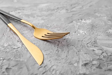 Photo of Elegant cutlery. Stylish knife and fork on grey textured table, closeup. Space for text
