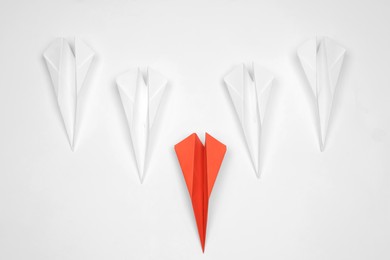 Photo of Handmade colorful paper planes on white table, flat lay. Leadership concept