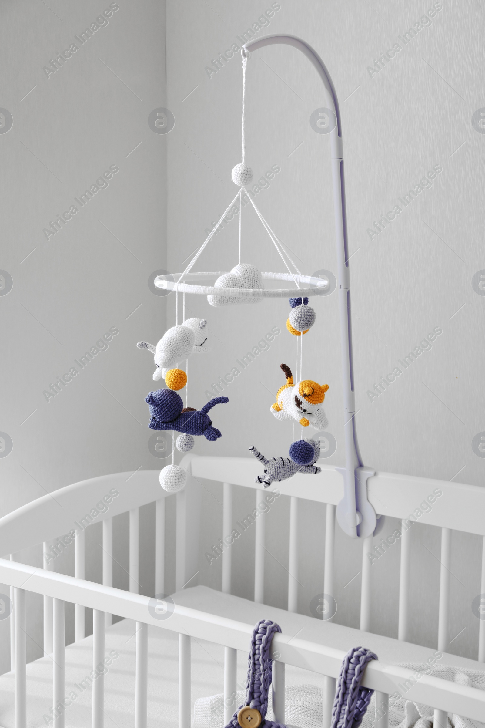 Photo of Modern crib with baby mobile in children's room. Interior design