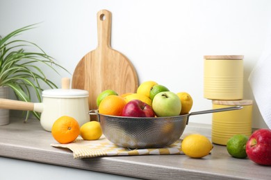 Photo of Metal colander with different fruits on countertop in kitchen