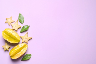 Delicious carambola fruits on violet background, flat lay. Space for text