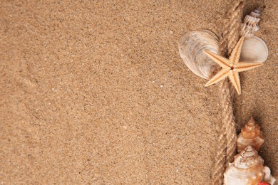 Photo of Beautiful sea star, shells and rope on sand, flat lay. Space for text
