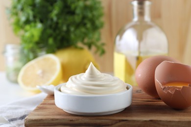 Photo of Fresh mayonnaise sauce in bowl and ingredients on table, closeup