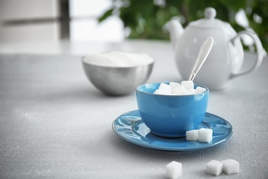 Cup with refined sugar cubes on table