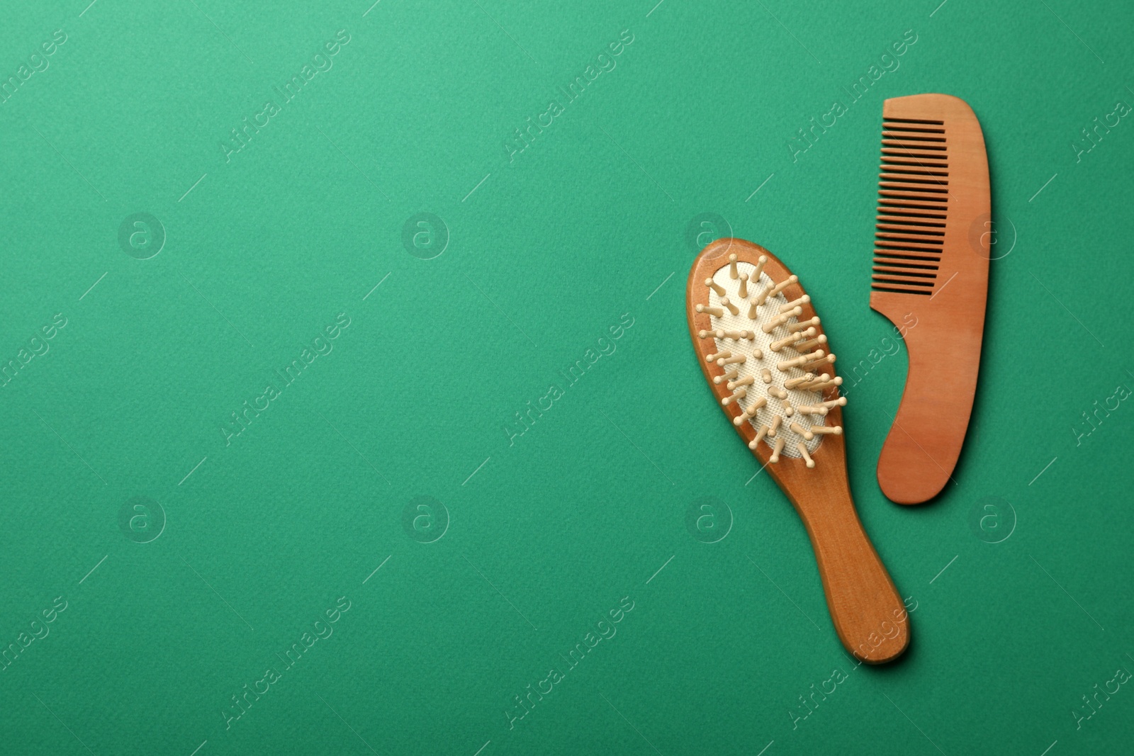 Photo of Wooden brush and comb on green background, flat lay with space for text. Conscious consumption
