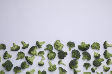 Many fresh green broccoli pieces on white background, flat lay. Space for text