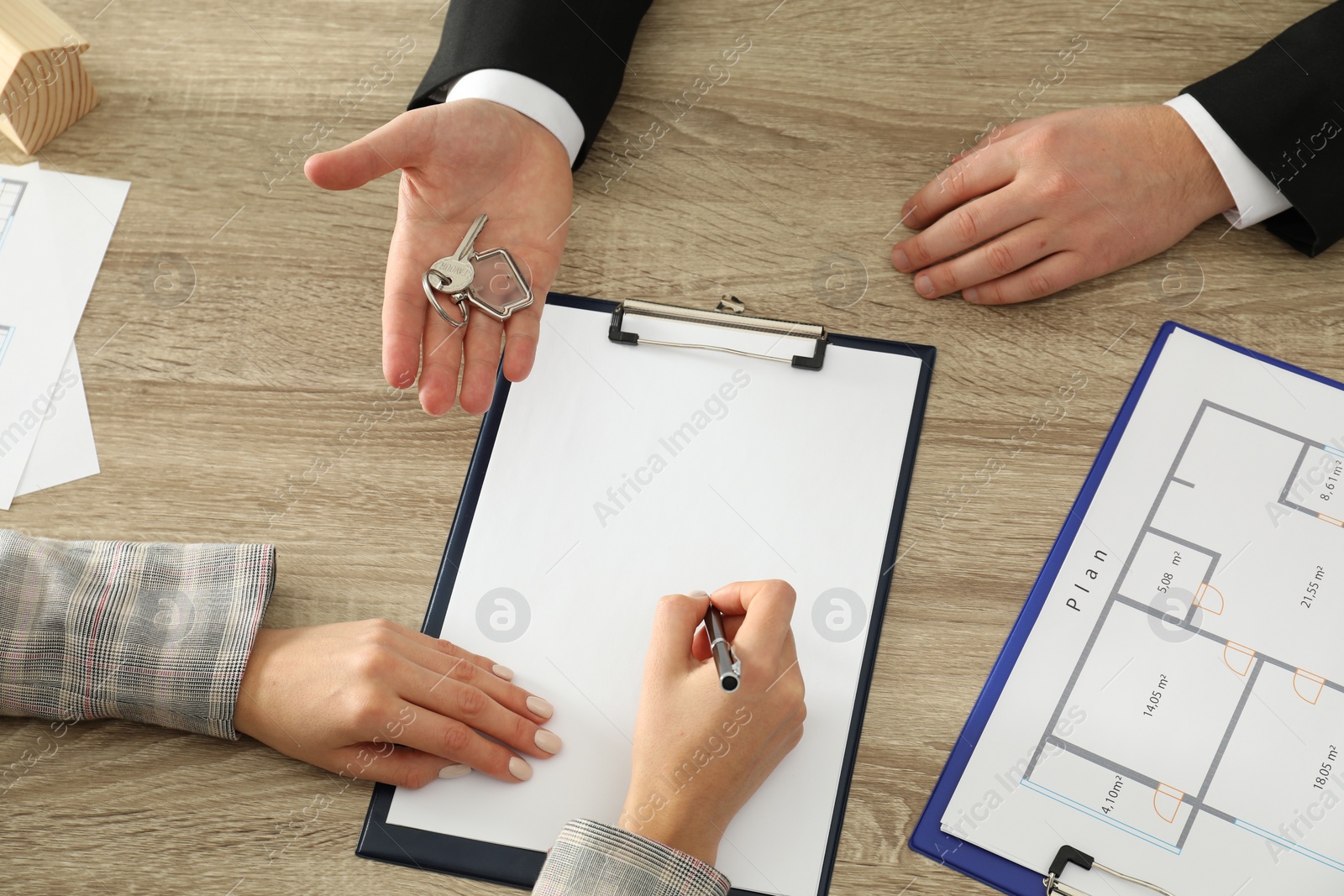 Photo of Real estate agent giving key to client at table in office, top view