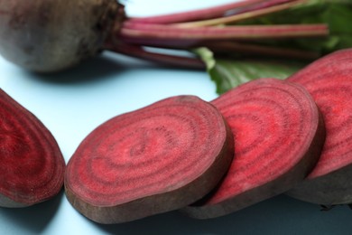 Whole and cut fresh red beets on light blue background, closeup