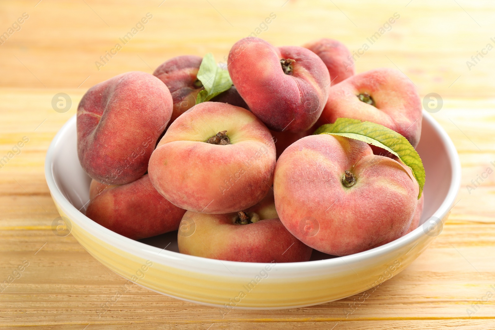 Photo of Fresh ripe donut peaches on wooden table, closeup