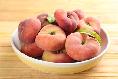 Photo of Fresh ripe donut peaches on wooden table, closeup