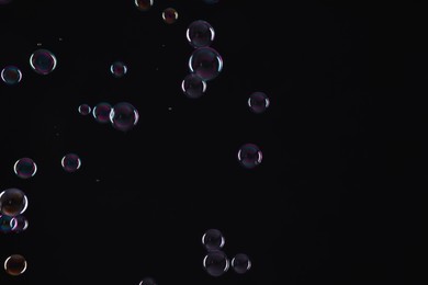 Photo of Many beautiful soap bubbles on black background. Space for text