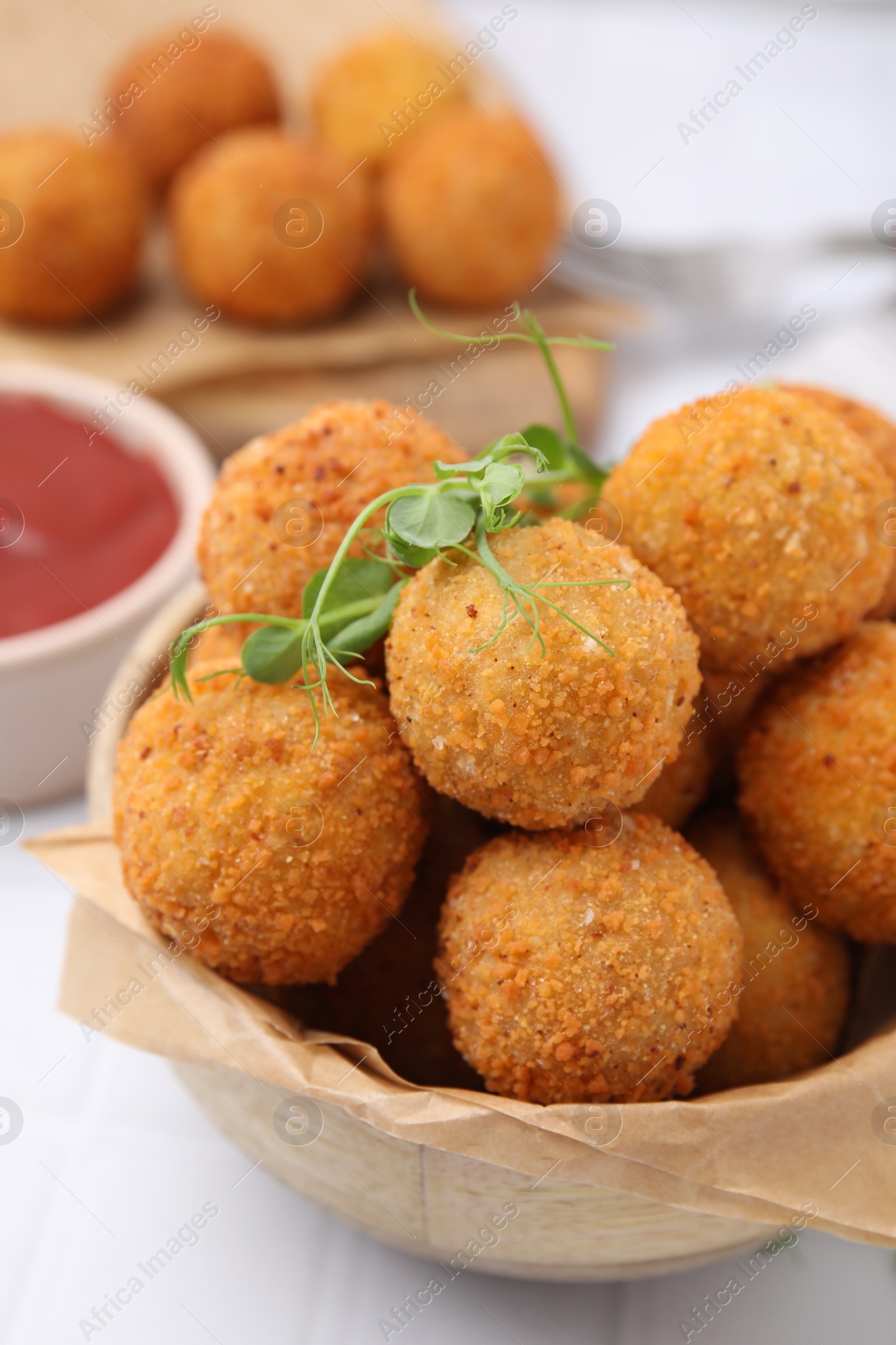 Photo of Bowl of delicious fried tofu balls with pea sprouts and ketchup on white tiled table, closeup