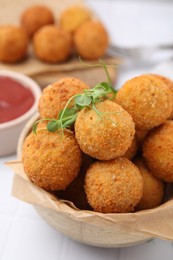 Bowl of delicious fried tofu balls with pea sprouts and ketchup on white tiled table, closeup