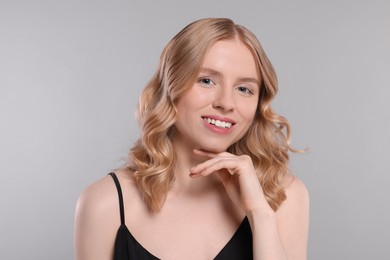 Portrait of beautiful woman with blonde hair on light grey background