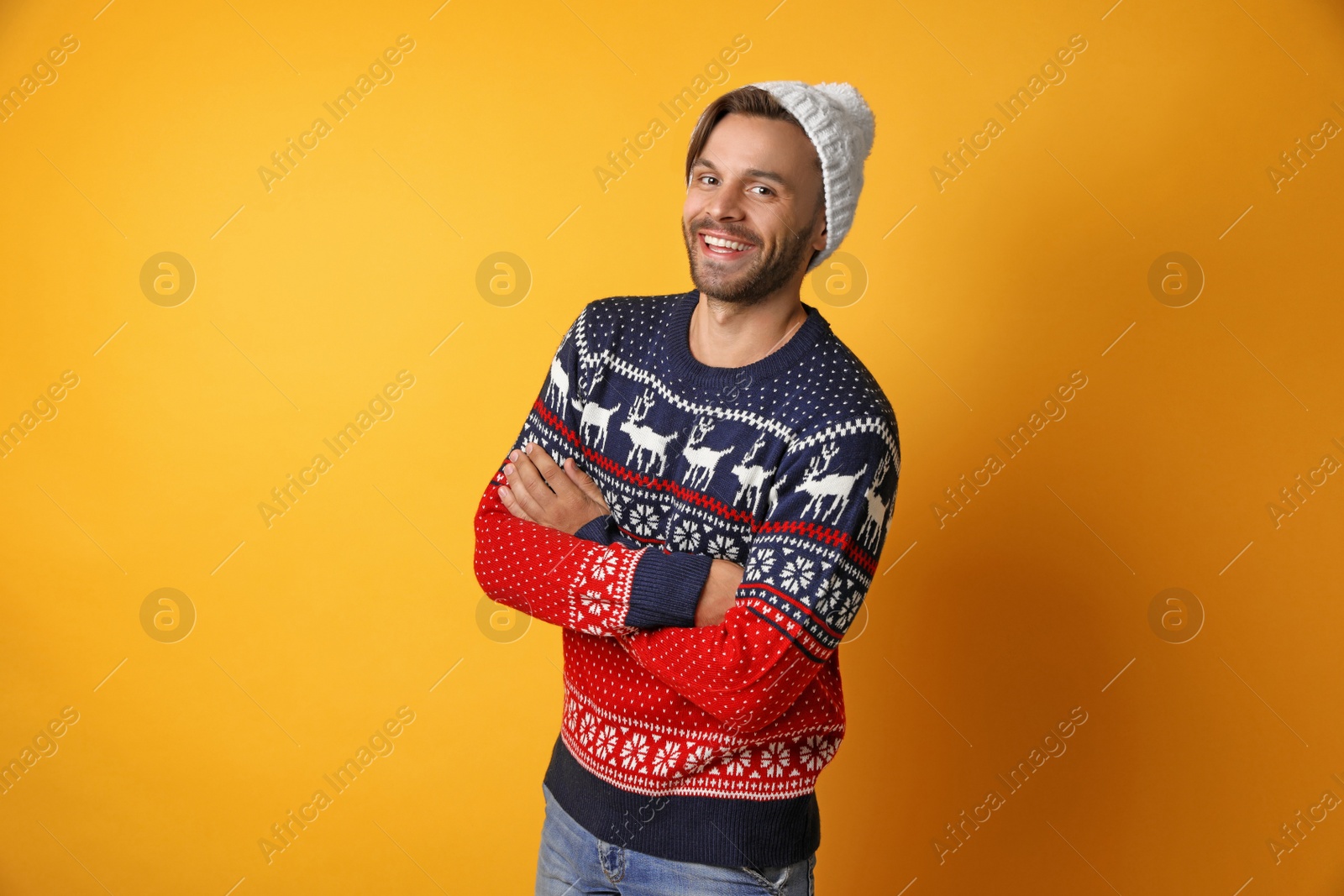 Photo of Young man in Christmas sweater and hat on yellow background
