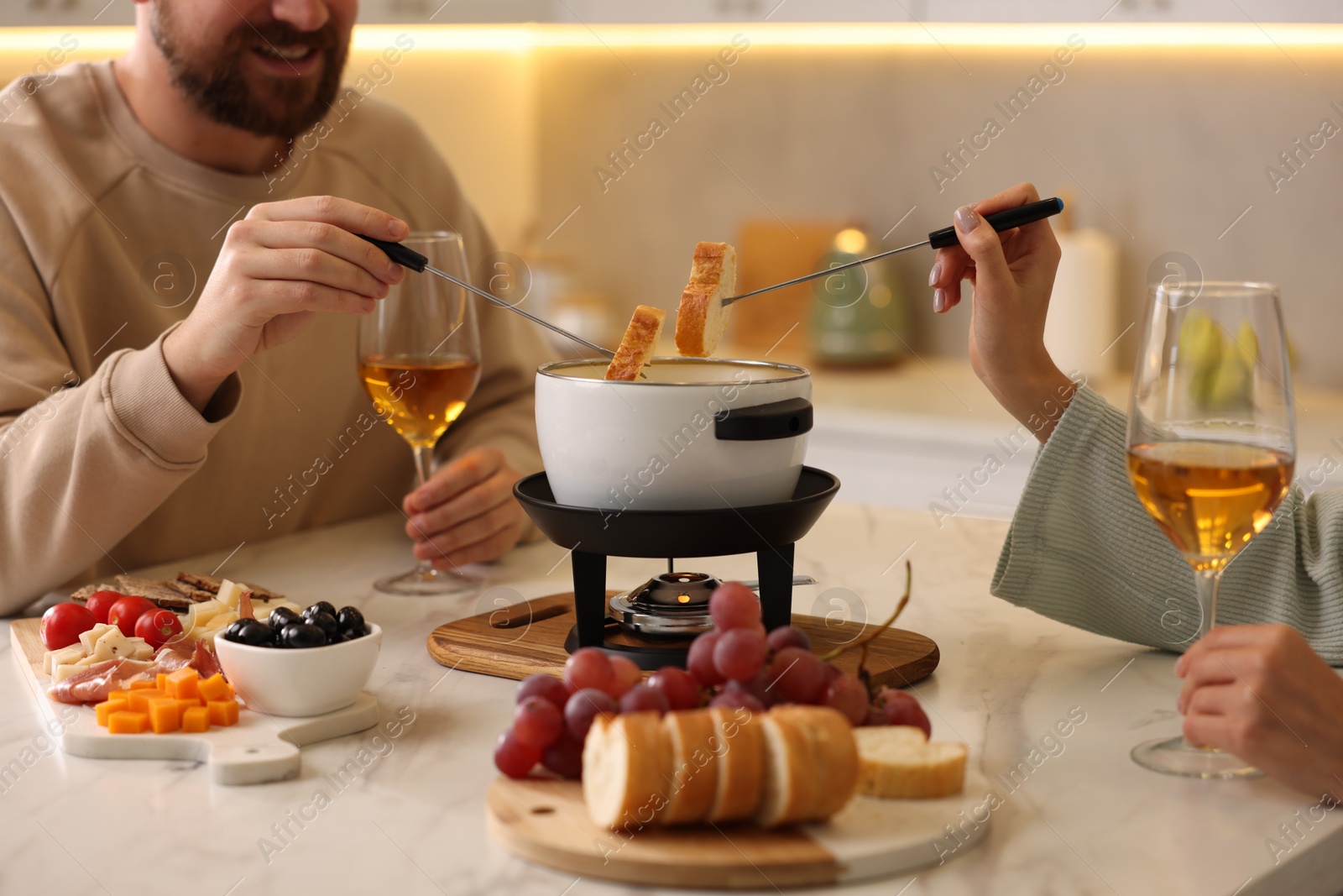 Photo of Couple enjoying fondue during romantic date in kitchen, closeup