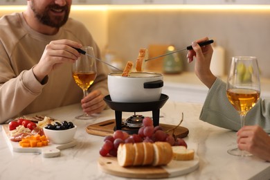 Photo of Couple enjoying fondue during romantic date in kitchen, closeup