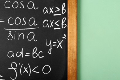 Chalkboard with many different math formulas on green wall, closeup