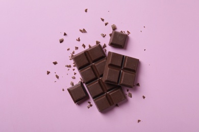 Photo of Tasty milk chocolate on pink background, flat lay