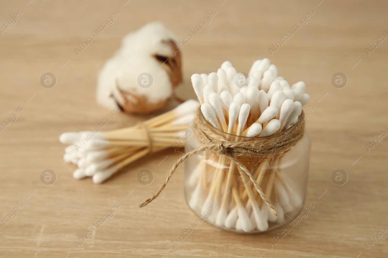 Photo of Cotton swabs and flower on wooden table, closeup