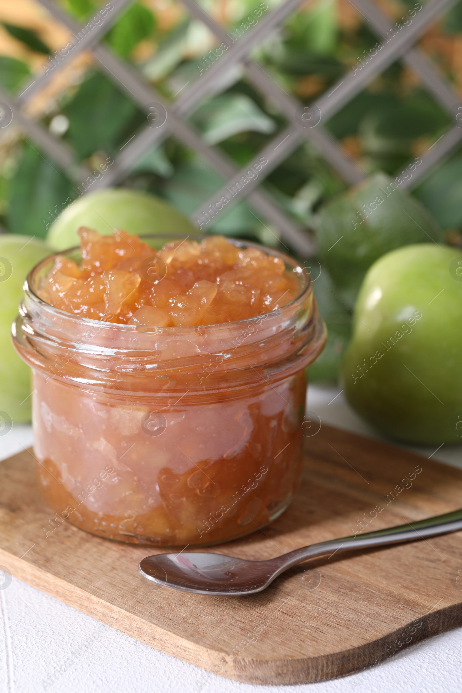 Photo of Glass jar of delicious apple jam and fresh fruits on white table, space for text