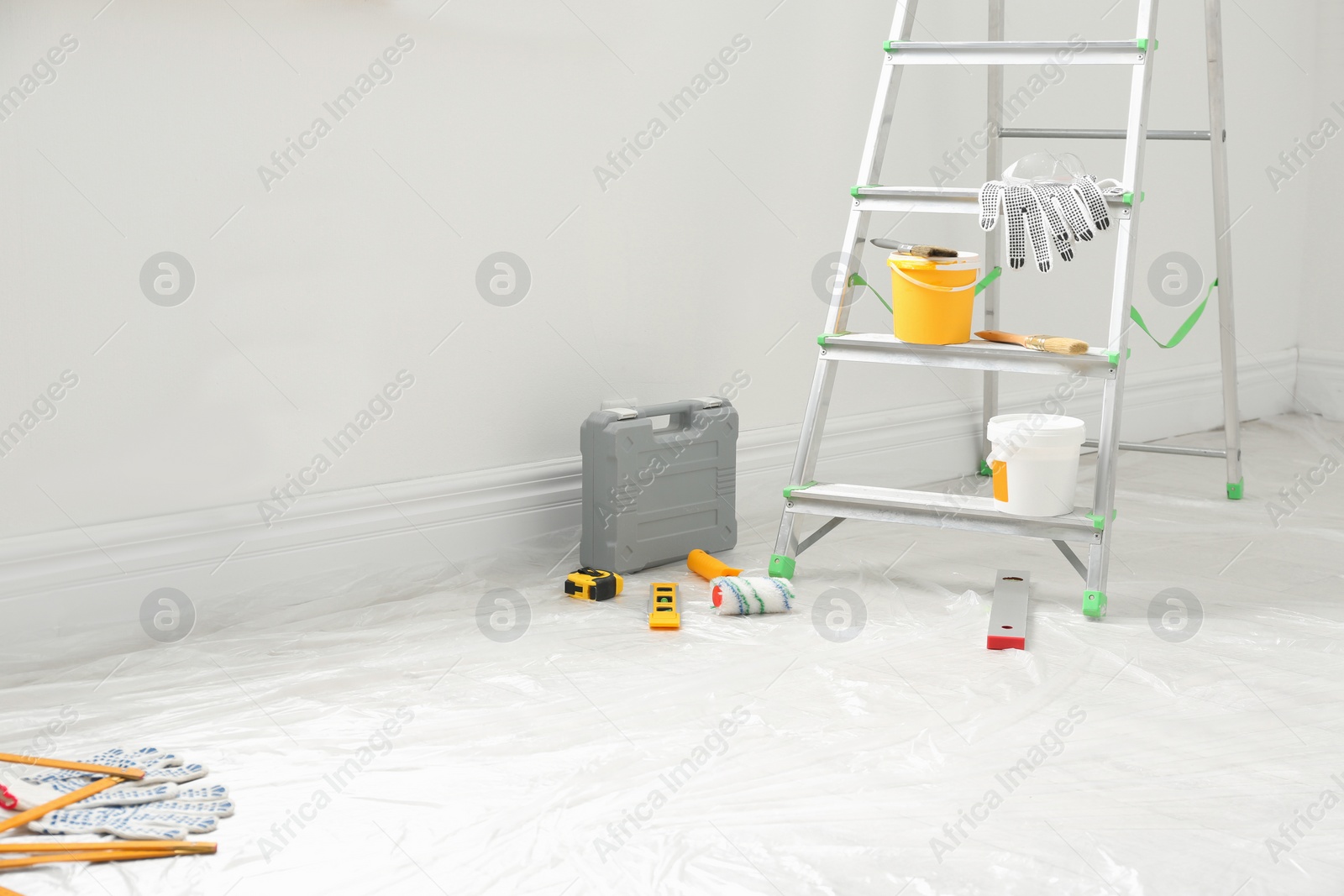 Photo of Stepladder and different tools near wall in room. Interior renovation