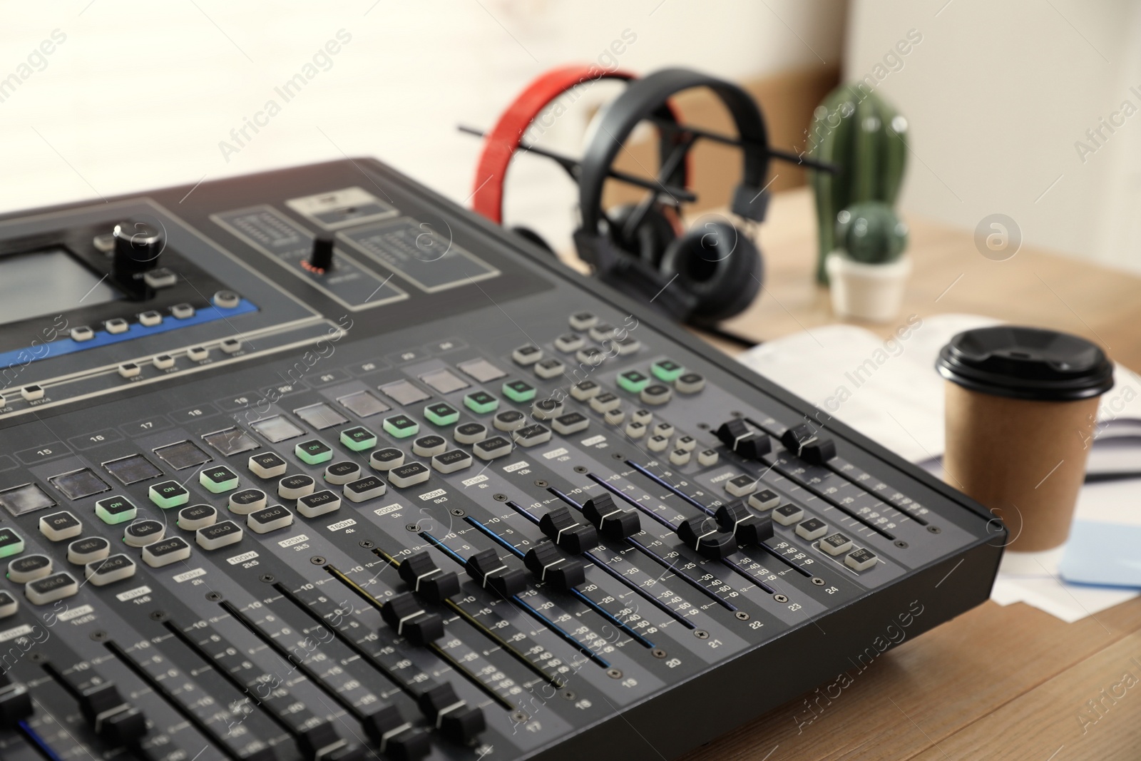 Photo of Professional mixing console on wooden table in modern radio studio, closeup