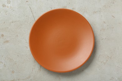 Empty orange ceramic plate on light grey table, top view