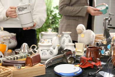 Photo of Many different stuff on black wooden table indoors. Garage sale