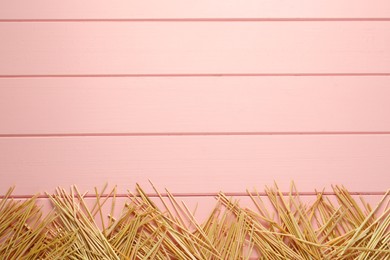 Photo of Heap of dried hay on pink wooden background, flat lay. Space for text