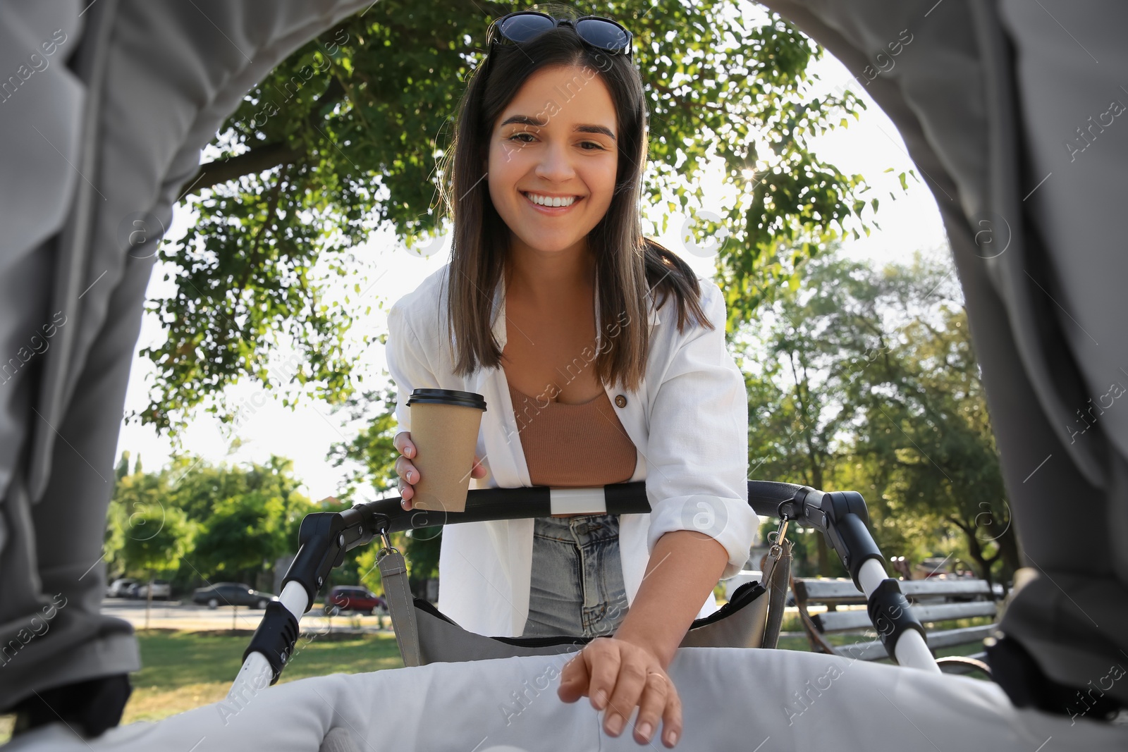 Photo of Young mother walking with her baby at park, view from stroller