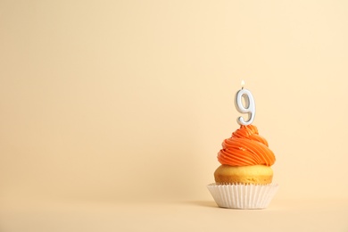 Birthday cupcake with number nine candle on beige background, space for text