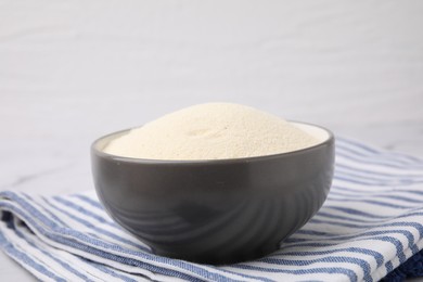 Photo of Bowl of uncooked organic semolina on table, closeup