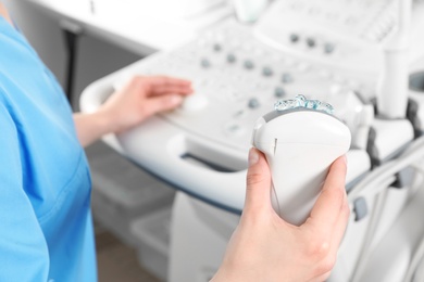 Professional sonographer using modern ultrasound machine in clinic, closeup