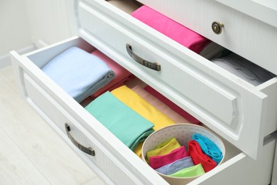 Chest of drawers with different folded clothes indoors