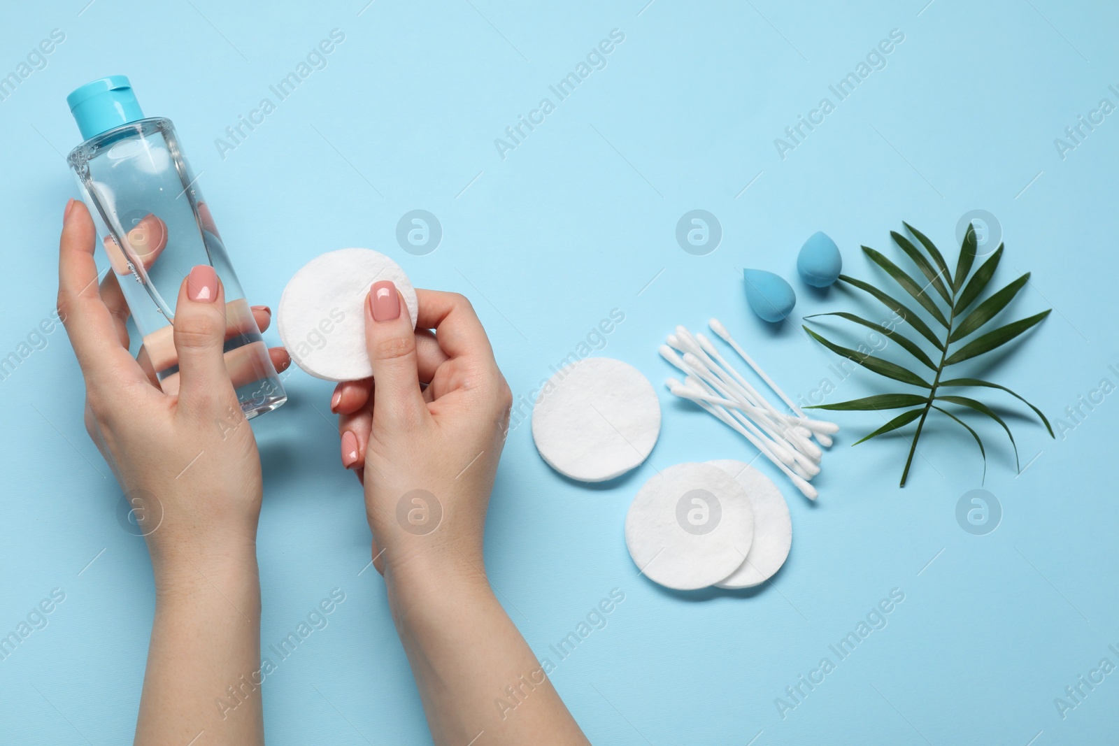 Photo of Woman with makeup remover, sponges, cotton pads and buds on light blue background, top view