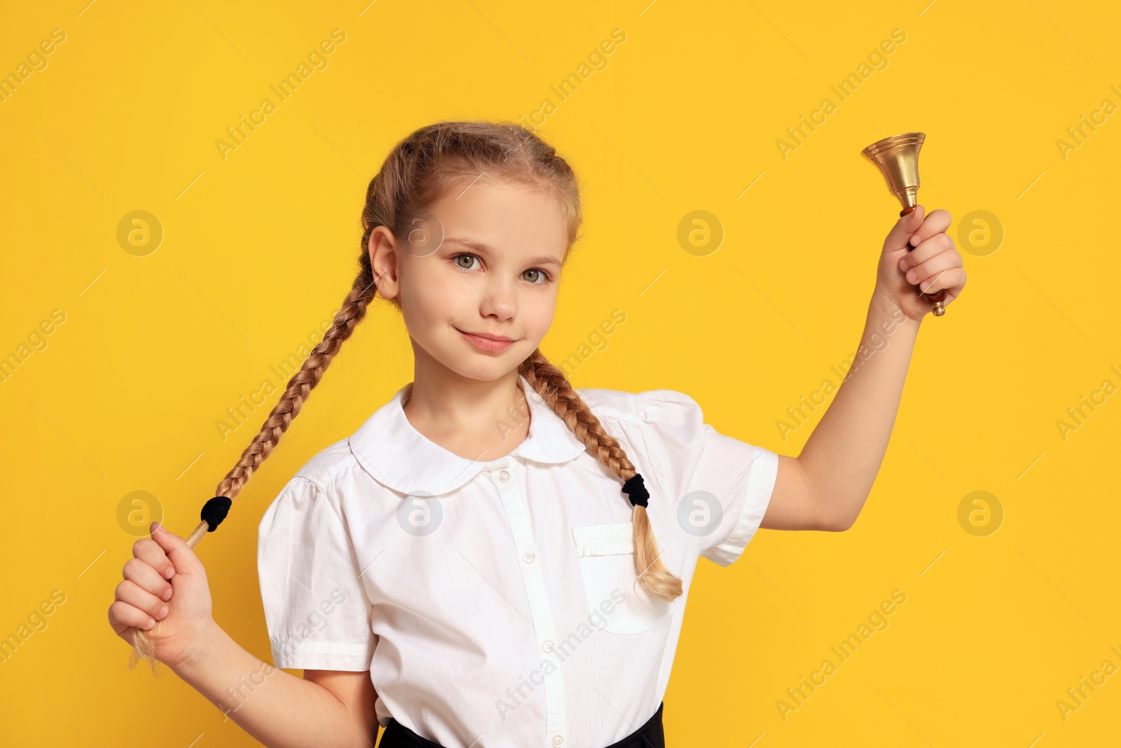 Photo of Pupil with school bell on yellow background