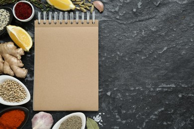 Photo of Blank recipe book and different ingredients on black textured table, flat lay. Space for text