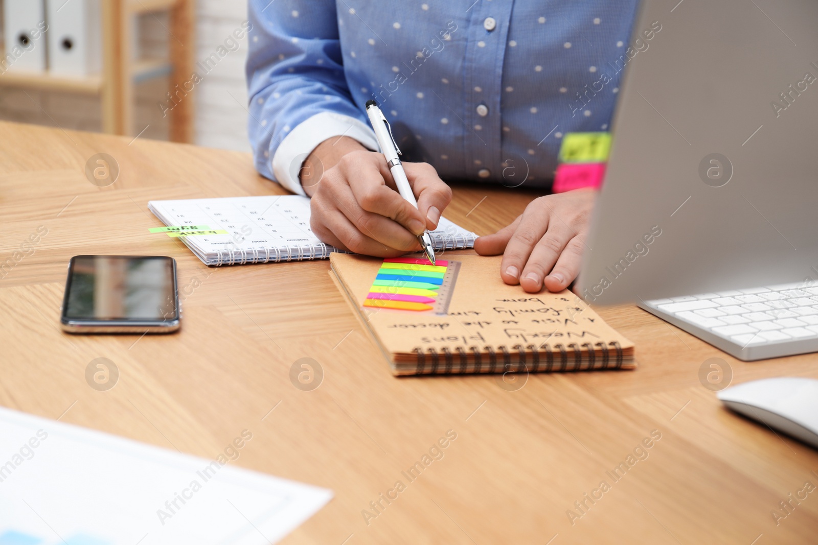 Photo of Woman making schedule using calendar at table in office, closeup