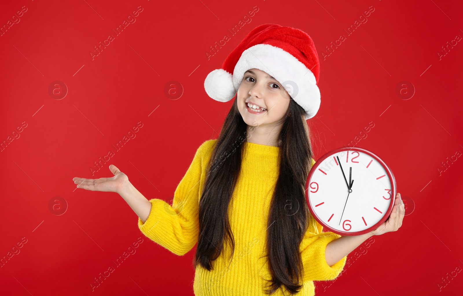 Photo of Girl in Santa hat with clock on red background. Christmas countdown