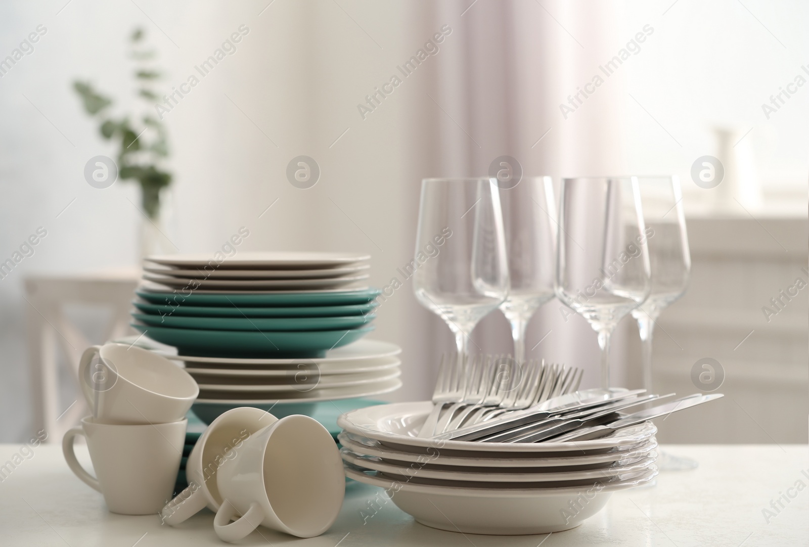 Photo of Set of clean dishware, cutlery and wineglasses on white table indoors