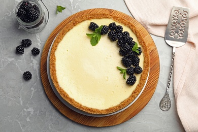 Delicious cheesecake decorated with blackberries on grey marble table, flat lay