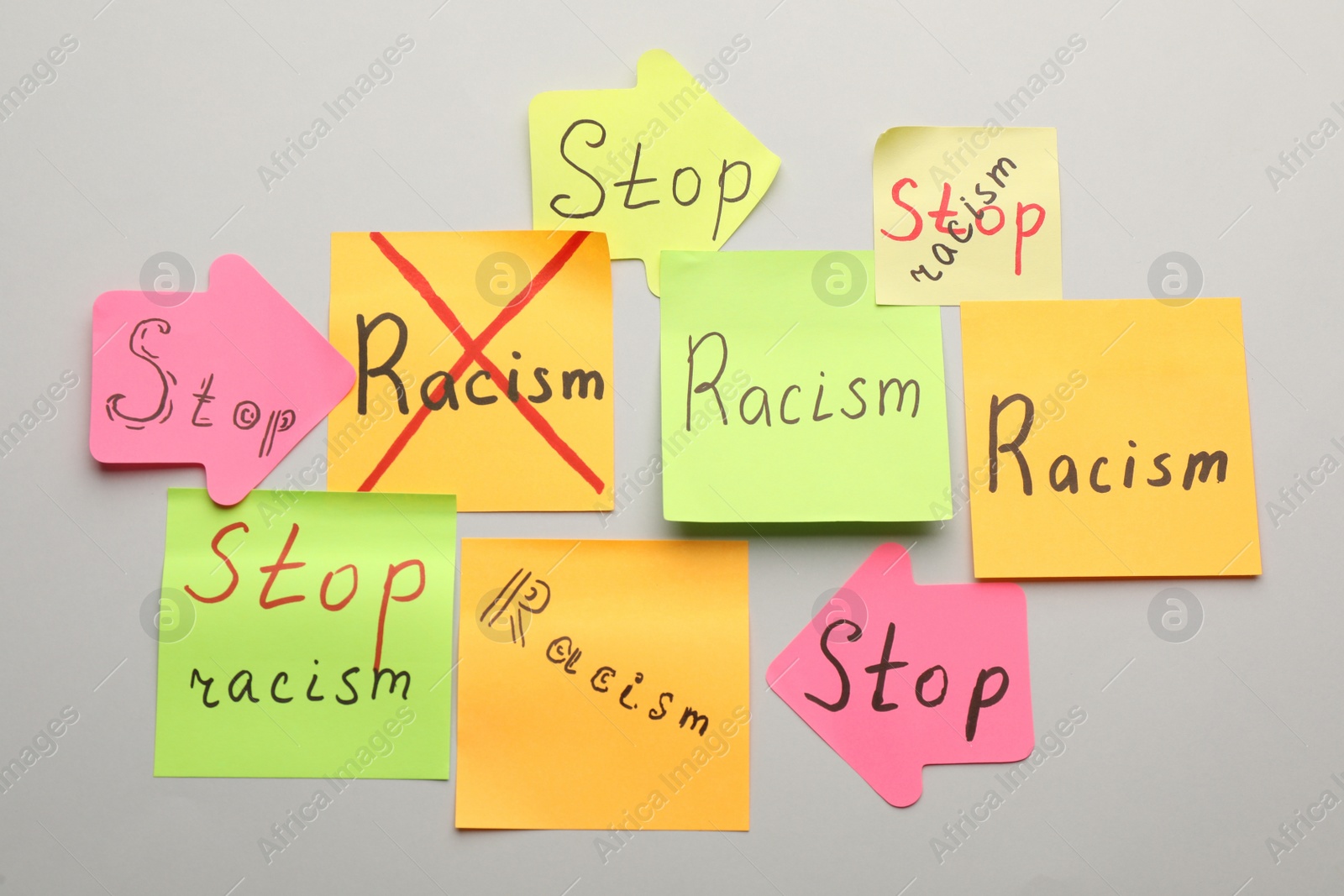 Photo of Paper notes with phrase Stop Racism on light background, flat lay