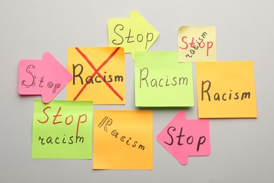 Photo of Paper notes with phrase Stop Racism on light background, flat lay