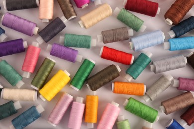 Photo of Set of colorful sewing threads on white background, flat lay